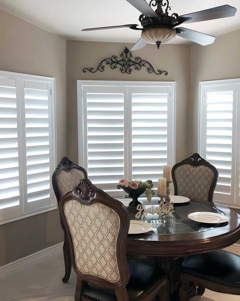 white plantation shutters across a breakfast nook with formal dining chairs