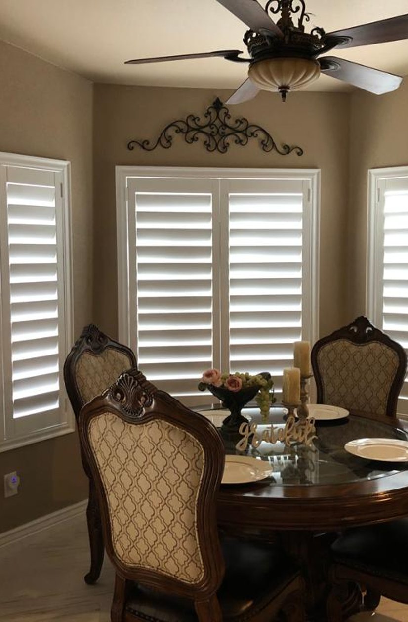 white plantation shutters in a breakfast nook with a round wood dining table